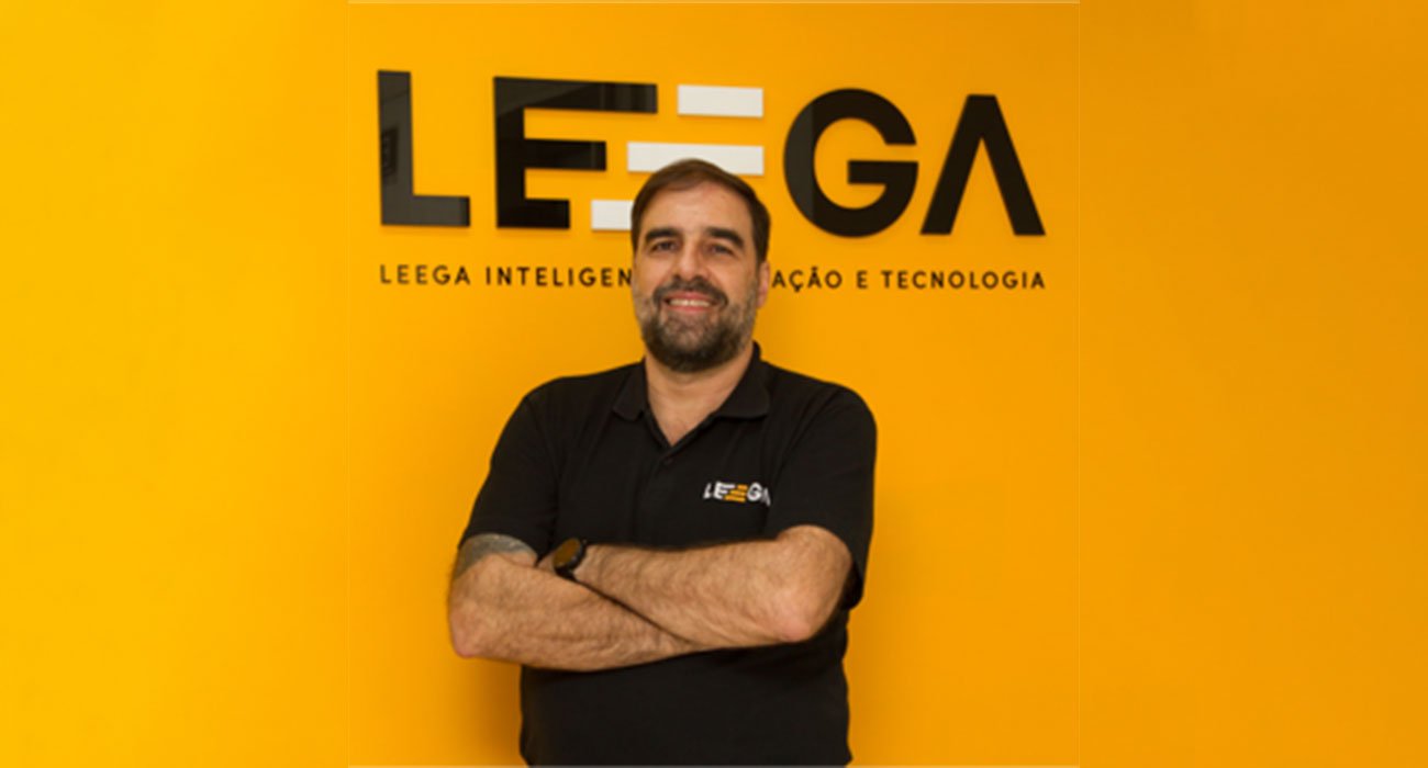 Paulo Amorim, diretor de Backoffice da Leega, em pose estratégica em frente à logo da Leega, representando a parceria estratégica com a JC Advisor para reforçar a segurança de dados empresariais.